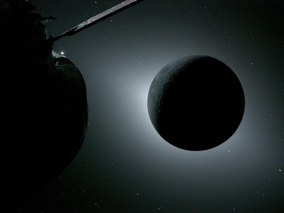 The dark disk of the Moon ringed by a soft glow of sunlight, with a solar array wing of the Orion spacecraft in the foreground at left and stars beyond
