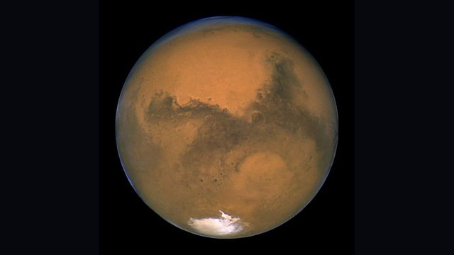 Mars photographed by the Hubble Space Telescope, showing dark surface regions and the southern polar cap
